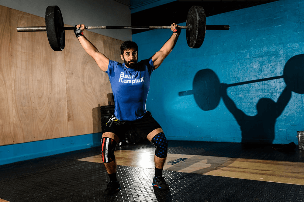 man lifting over his head wearing stars and stripes knee sleeves