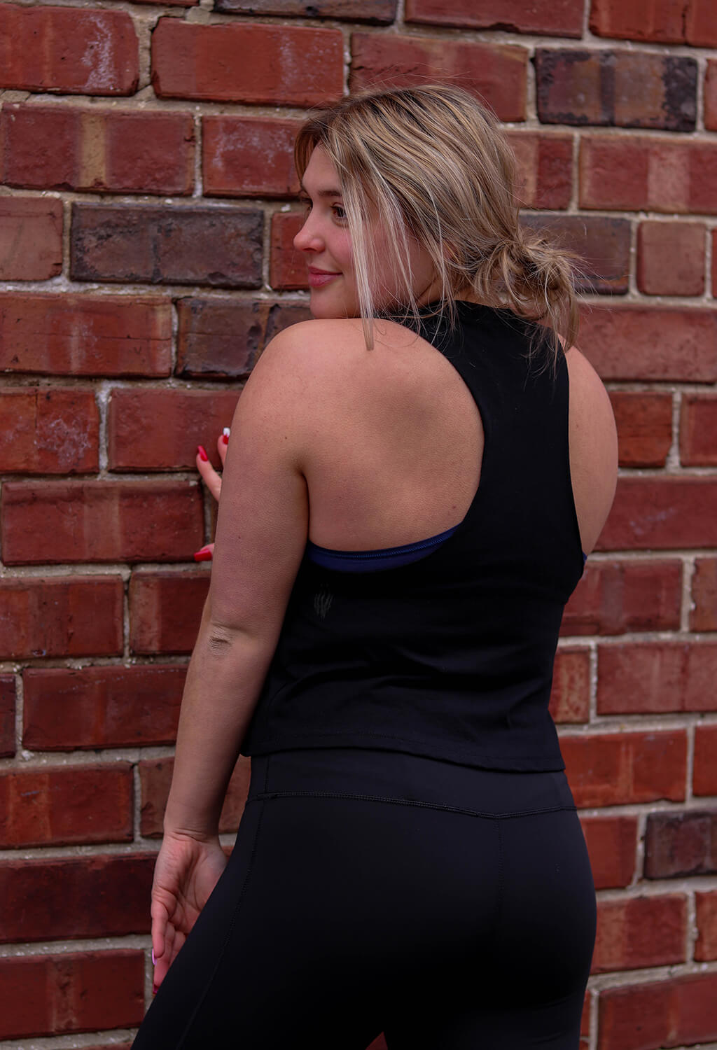 Woman showing Black BKX Racerback Crop back view