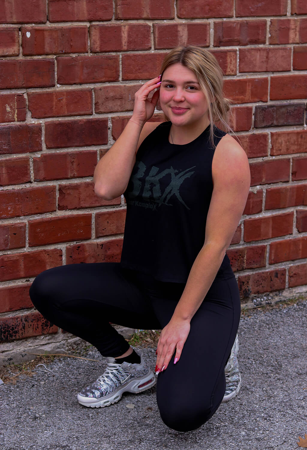 Woman kneeling wearing Black BKX Racerback Crop Front view