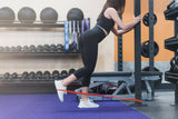 woman using red resistance band to work out