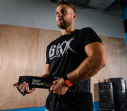 Man putting on BKX - Strength Belt w/ 6" back for added support before workout