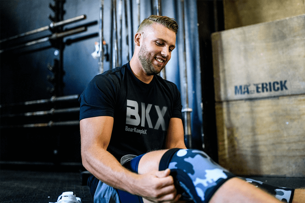 man putting on knee sleeves