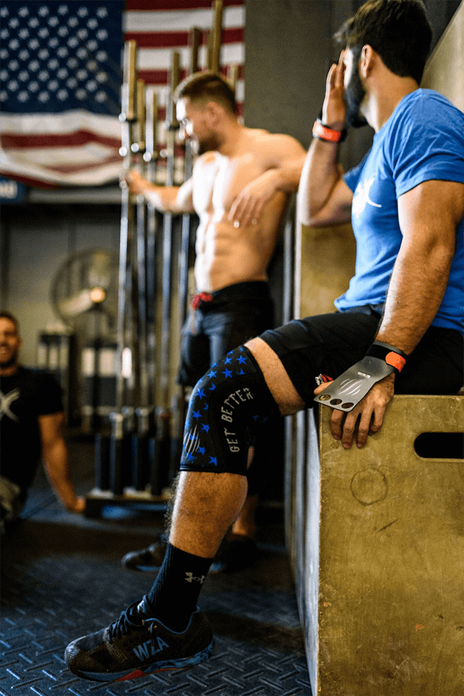 man resting wearing bear komplex gloves and knee sleeves