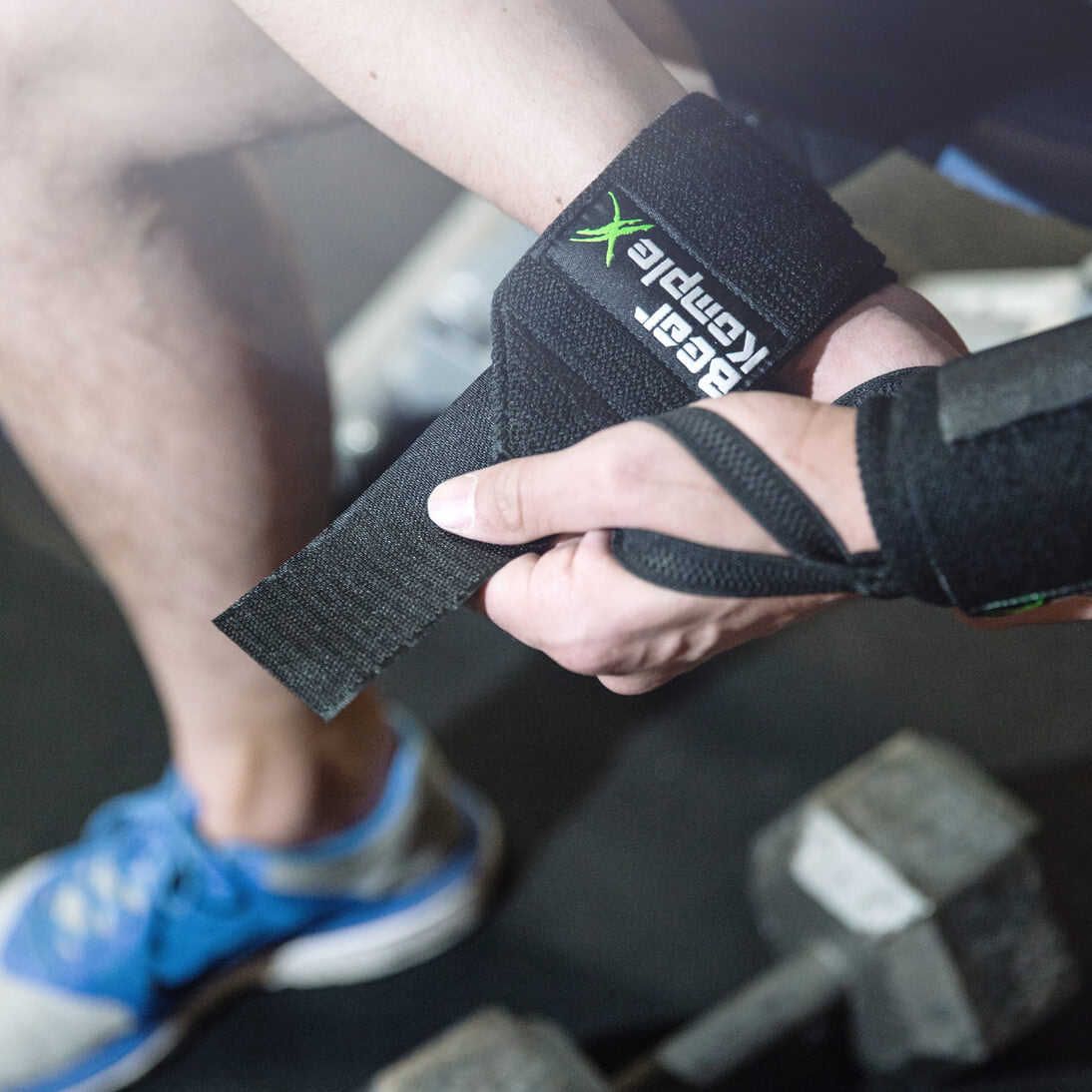 man strapping on Bear KompleX Wrist Wraps on barbells