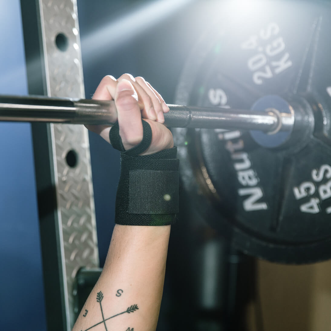 closeup of hand lifting heavy weights wearing Bear KompleX Wrist Wraps 