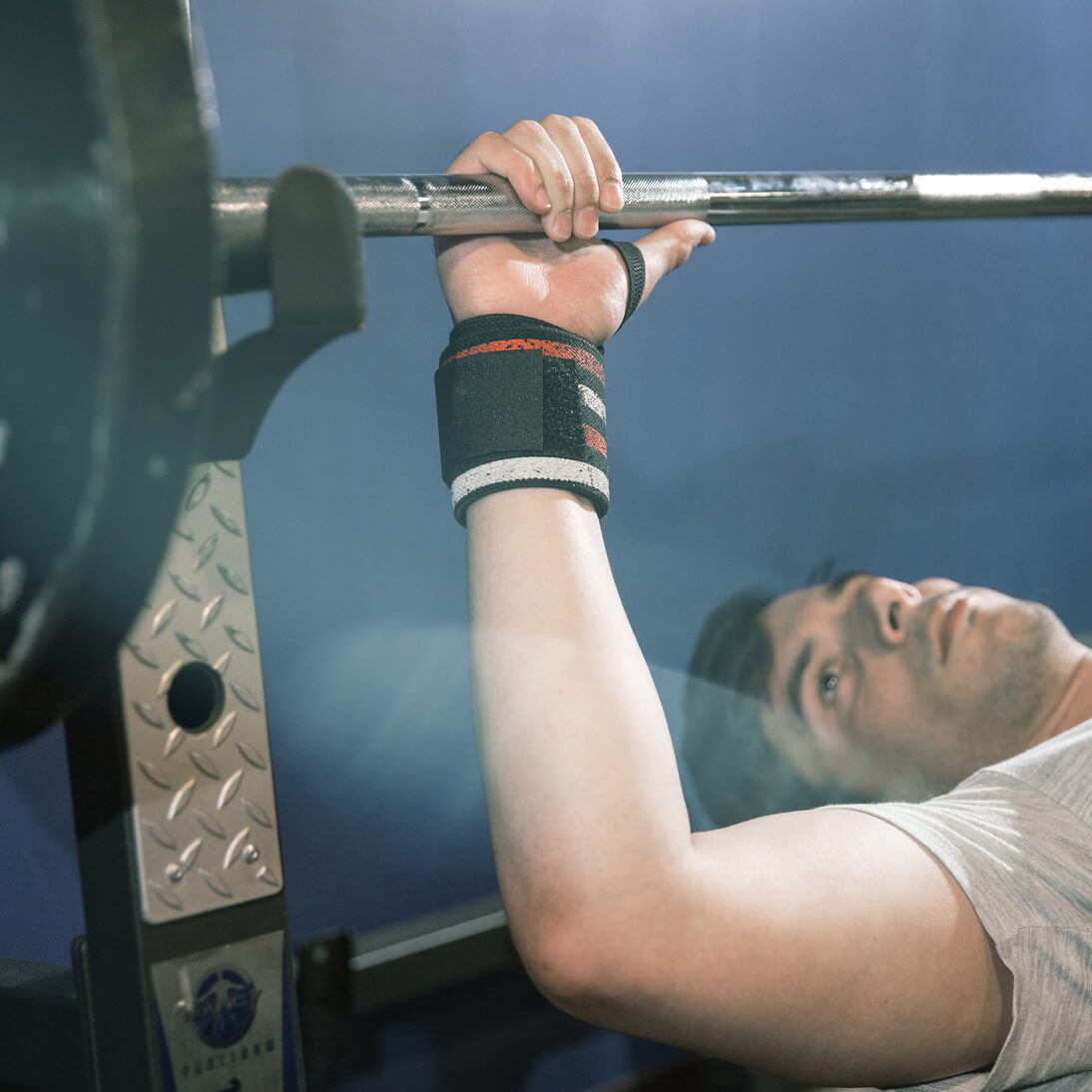 Men adjusting grip before benching heavy weight and wearing stars and stripes wrist wraps