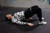 Woman laying down stretching hips with black resistance band