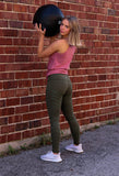 Woman wearing BKX Military Green/Tripwire Leggings while working out against brick wall